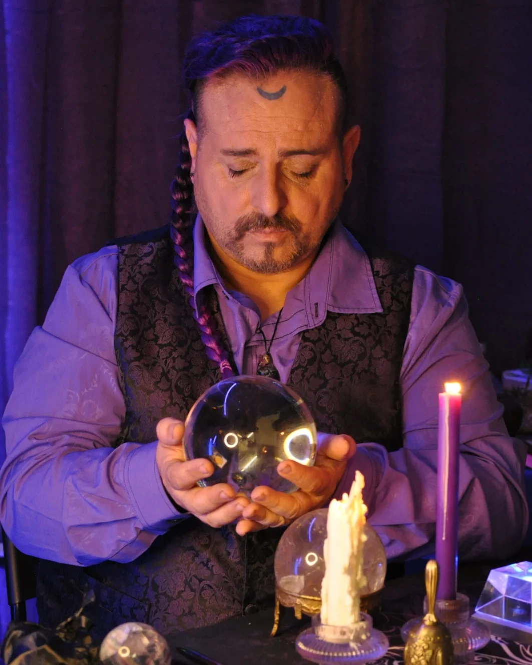 José Cuy sosteniendo una esfera de cristal junto a unas velas
